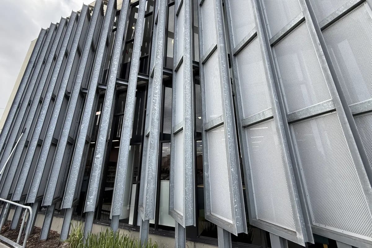 Tall shopping centre glass behind a metal louvre screen